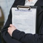 Osoba trzymająca na clipboardzie dokument polisy ubezpieczeniowej