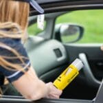 Policjant drogówki przeprowadza badanie alkomatem kierowcy w samochodzie