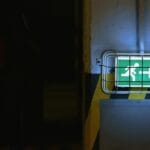 Zielony podświetlony znak wyjścia ewakuacyjnego z białą strzałką