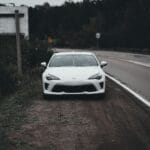 Białe auto sportowe zaparkowane przy drodze pod pochmurnym niebem
