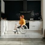 Kobieta na wózku inwalidzkim porusza się po nowoczesnej kuchni