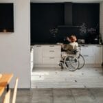 Kobieta na wózku inwalidzkim w przytulnej kuchni z tablicą kredową