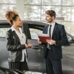 Kobieta rozmawia z doradcą o zakupie auta w salonie samochodowym