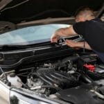 Mechanik naprawia silnik samochodu na zewnątrz w ciągu dnia