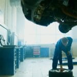 Mechanik w niebieskim kombinezonie sprawdza oponę auta w warsztacie