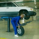 Mechanik wymienia oponę w podniesionym SUV‑ie w warsztacie samochodowym
