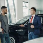 Para rozmawia ze sprzedawcą w salonie, wybierając auto z importu