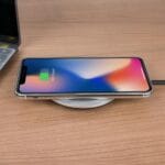 Smartfon ładujący się bezprzewodowo obok laptopa na biurku