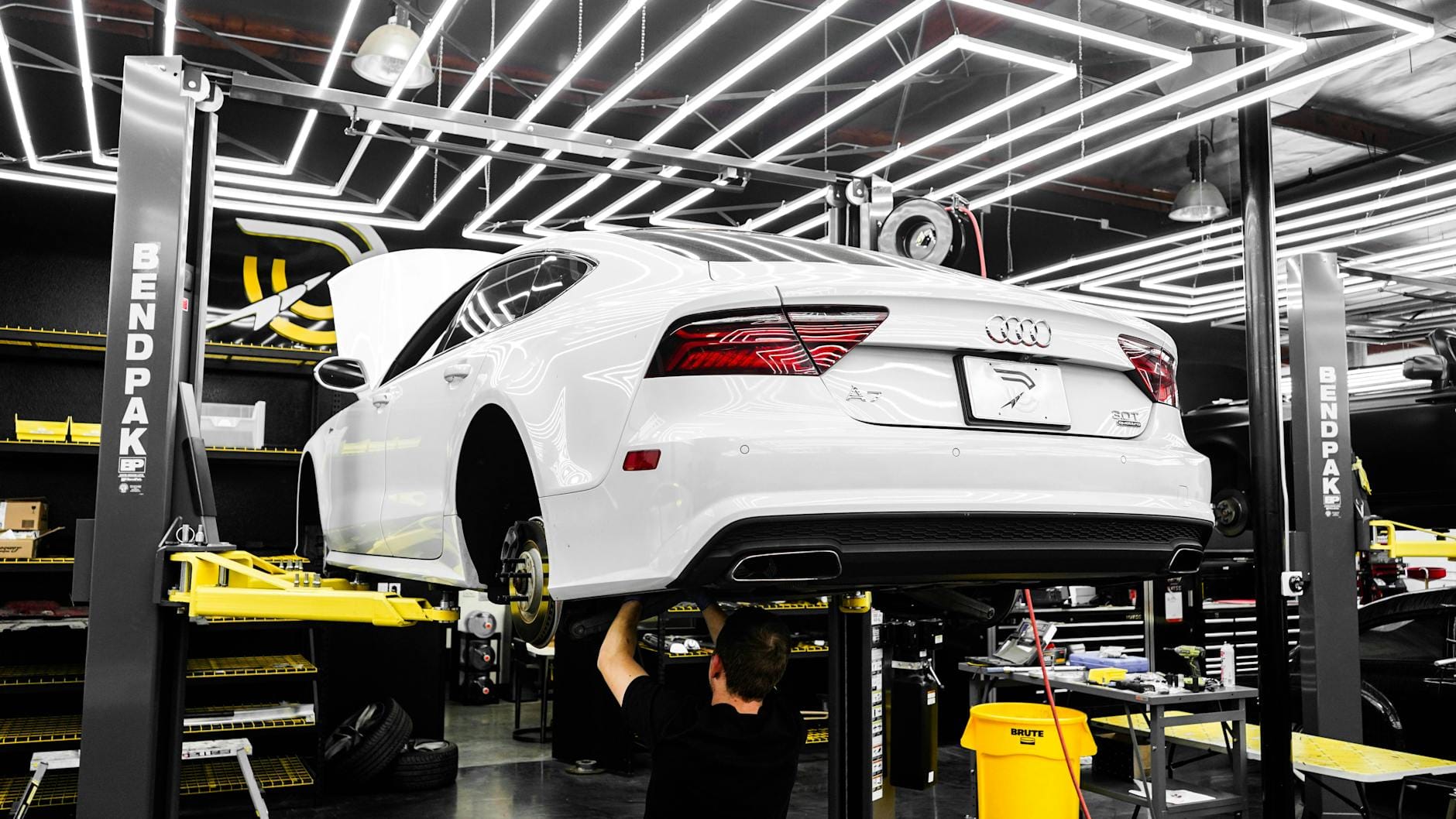 Mechanik serwisuje białe BMW w nowoczesnym warsztacie