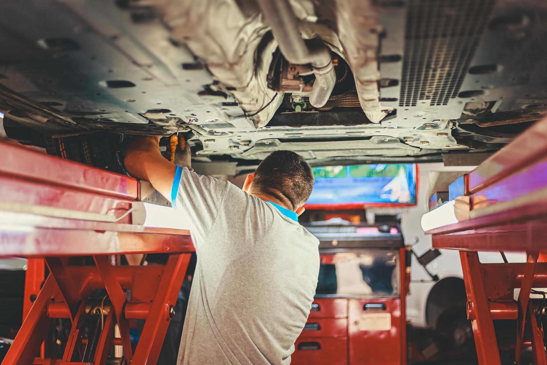 Mechanik w niebieskim kombinezonie sprawdza silnik auta w garażu