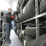 Mechanik układa oponę na regale w magazynie przechowywania opon