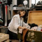 Młoda kobieta przegląda ubrania w przytulnym sklepie z odzieżą vintage