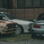 Zardzewiałe auto zabytkowe obok nowoczesnych samochodów w mieście