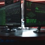 Dwa monitory z zielonym kodem w ciemnym pokoju, motyw cyberbezpieczeństwa