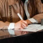 Kobieta podpisuje dokument przy nowoczesnym biurku w urzędzie